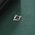 Macro shot of a silver planet charm with a Saturn-like ring on textured green paper - Steel Color Style 2