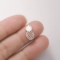 Macro shot of a hollow pineapple stainless steel pendant charm held by fingers - Pineapple Shape - Steel Color
