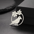 Macro detail of silver stainless steel bird and flower pendant on dark gift box background - Steel