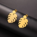 Gold monstera leaf dangle earrings in stainless steel on black display pedestal - Gold