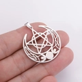 Handheld view of a vintage stainless steel triple moon pentagram pendant with Celtic knots - Steel