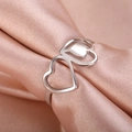 Polished silver double heart interlocking ring displayed on luxury pink silk fabric - US 7 / Steel