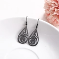 Water-drop hollow swirl earrings in matte black finish on a white ceramic plate - Black