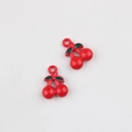Macro shot of red cherry alloy pendants with green leaves and glossy enamel finish - Cherry