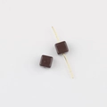 Macro detail of dark brown acrylic cube beads with hole showing the threading process - Brown