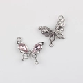 Macro detail of silver bow pendant with pink teardrop crystals and dual link rings - Silver / Pink