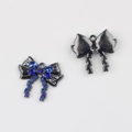 Primer plano de colgantes de lazo con diamantes azules sobre acabado gris oscuro - Base Negro de Fusil Strass Azul