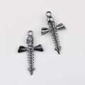Detalle macro del colgante de cruz gótica con calavera y columna vertebral en negro - Gris metalizado