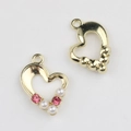 Macro view of gold heart pendants with pink rhinestones and white pearls for DIY jewelry - Gold / Pink
