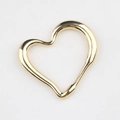 Macro view of gold-tone hollow heart pendant with elegant fluid streamlined design - Gold