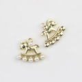Macro shot of gold rocking horse pendants with white pearl inlay and metal hangers - Gold Base Pearl