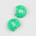 Macro shot of green cookie-shaped acrylic beads with M letter and colorful dots for DIY - Green