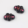 Macro shot of cloud-shaped acrylic beads with HI lettering and pink stars for DIY jewelry - Black