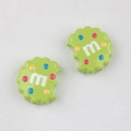 Close-up of green cookie shaped resin charms with m letter and colorful dot patterns - Apple Green
