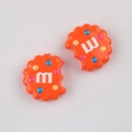 Close-up of orange cookie-shaped acrylic beads with M letter and colorful dots for DIY - Orange