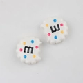Macro detail of bitten cookie acrylic beads with colorful dots and letter M for DIY - White