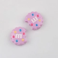Macro detail of purple cookie-shaped resin beads with colorful dots and 'm' logo - Purple