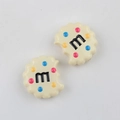 Macro detail of cream-colored cookie resin charms with M-letter and colorful dots - Beige