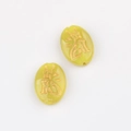 Macro shot of oval Czech glass beads in light green with golden dragon character carving - Yellow (00850901)