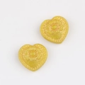 Makro-Detail von herzförmigen tschechischen Glasperlen mit vergoldeter Dahliengravur - Gelb