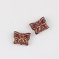 Detailed close-up of dark red glass butterfly beads with vintage gold gilded wing patterns - Transparent Dark Purple