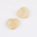 Macro view of heart-shaped Czech glass beads with gold floral etching for DIY crafts - Clear White