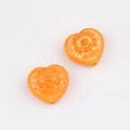Detailed macro view of orange heart-shaped glass beads with intricate golden flower patterns - Orange