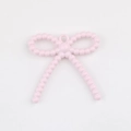 Detalle de un colgante de lazo rosa en aleación con textura de cuentas para joyería DIY - Rosa
