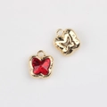 Macro detail of butterfly jewelry charms with red zircon inlay and gold plated metal frames - Gold / Red