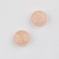Makroaufnahme von rosa Glasperlen mit doppelseitiger goldener Schneeflocken-Gravur - Rosa