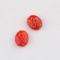 Macro view of red glass beads featuring golden embossed shamrock clover patterns - Red