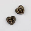Macro detail of heart-shaped Czech glass beads with vintage gold floral pattern - Black