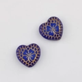 Macro view of blue heart-shaped Czech glass beads with intricate gold floral engraving - Dark Blue