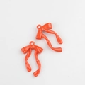 Macro detail of glossy orange bow pendants with wavy ribbons for DIY jewelry making - Orange
