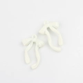 Close-up of cream white ribbon bow pendants in alloy finish for DIY jewelry crafts - White