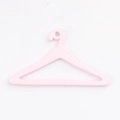 Dettaglio di una piccola gruccia rosa per vestiti da bambola con gancio minimale - Rosa