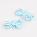 Detail view of two light blue matte bow pendants with dual loops for DIY jewelry making - Blue