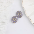 Detailed macro of vintage purple Czech glass beads with embossed gold flower patterns - Purple