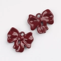Close-up of a pair of dark red lacquer bow charms with metal rings for DIY jewelry making - Fuschia