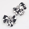 Close-up of metallic silver bow charms for DIY jewelry making with a polished mirror finish - Silver
