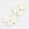 Detail of two cream white alloy bow pendants with glossy enamel finish for DIY jewelry - White