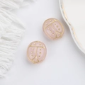Macro detail of two pink hand-painted ladybug glass beads with gold accents for DIY crafts - Pink