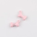 Close-up of pink bone-shaped alloy pendants with paw prints for DIY jewelry making - Pink