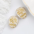 Macro shot of Czech glass skull beads with vintage gold hand-painted sun and spiral motifs - Milky White