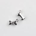 Close-up of bone-shaped metal pendants with paw print for DIY jewelry making - Silver