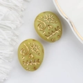 Close-up of Czech glass beads with gold painted sun face and totem patterns for jewelry DIY - Yellow