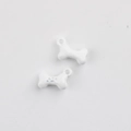 Close-up of white enamel bone charm with paw print detail and hanging loop for DIY jewelry - White