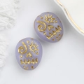 Macro shot of light purple glass beads with gold painted skull for DIY jewelry making - Lavender