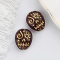 Macro detail of Czech glass beads with gold skull engraving for DIY jewelry making - Dark Coffee