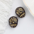 Detail of Czech glass beads with gold-painted skull designs for DIY jewelry crafts - Dark Purple